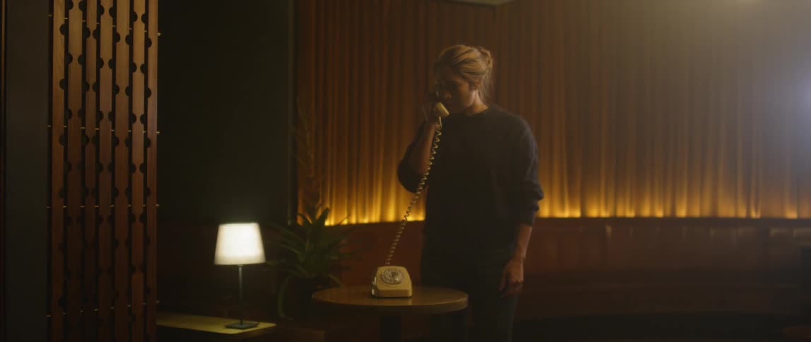 A woman walks over and picks up the phone