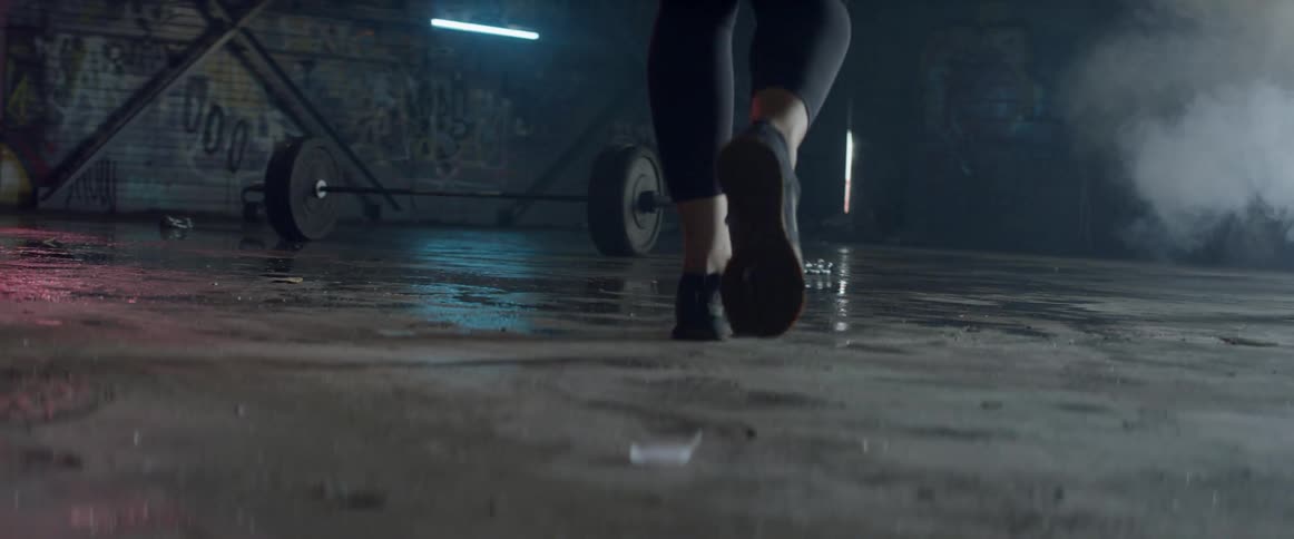 Woman is walking toward barbell with plate weights