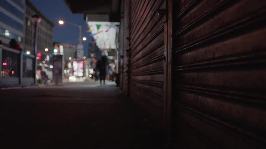 Pedestrians are walking on an urban sidewalk on a cold night