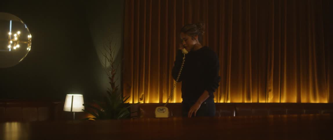 A woman uses a corded phone inside a restaurant