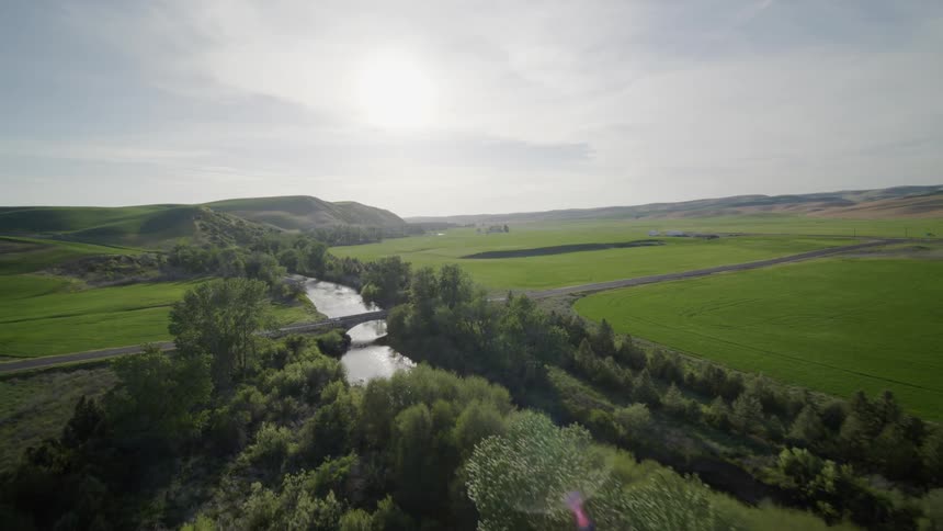Pullback reveal of a rural road river bridge surrounded by lush and rich farmland