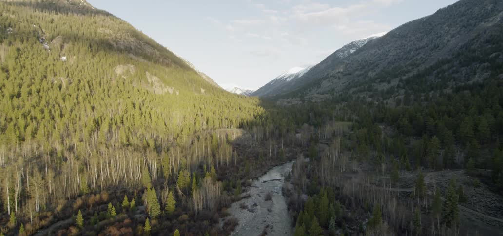 A creek sits between the mountains under a blue sky