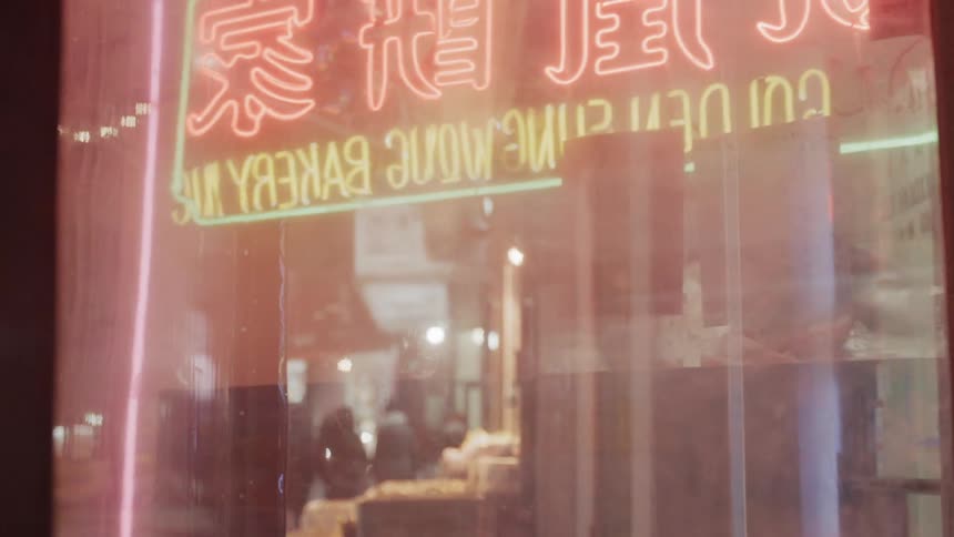 A chinese restaurant in a city with a neon on the window at night