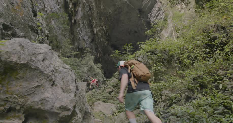 A group of people hike up towards a cave