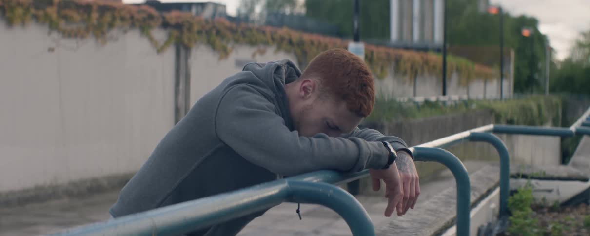 Man leans against a railing as he breathes heavily