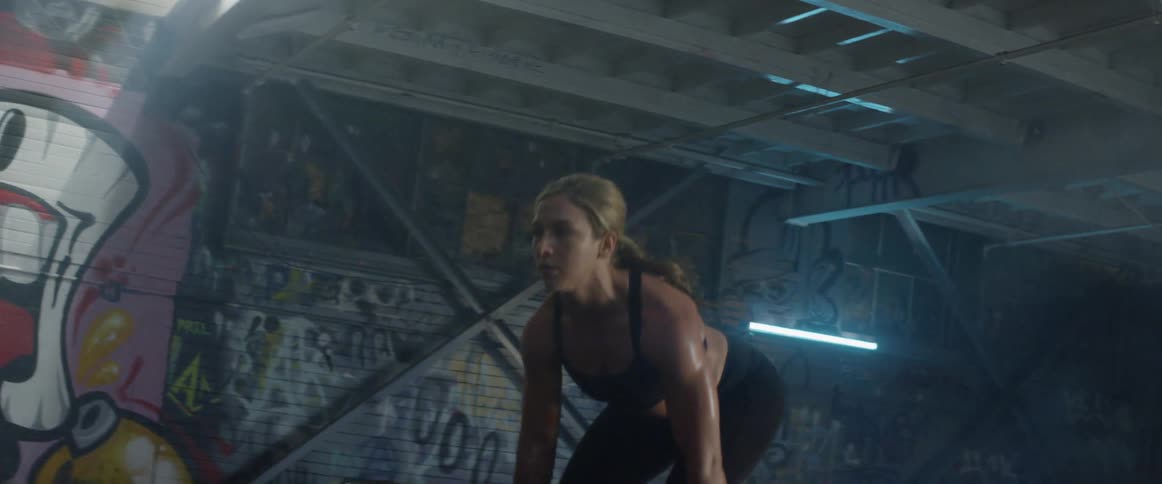 A woman crouches a heavy weight