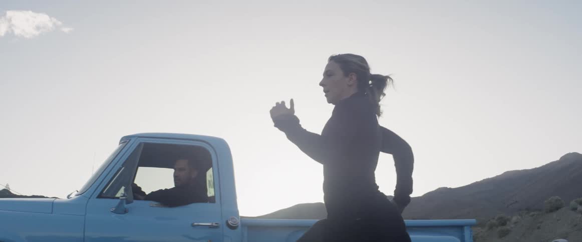 A woman races alongside a moving truck
