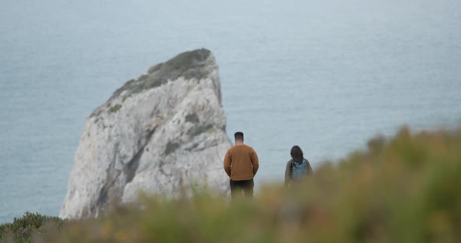 Man and woman walk on a coastline