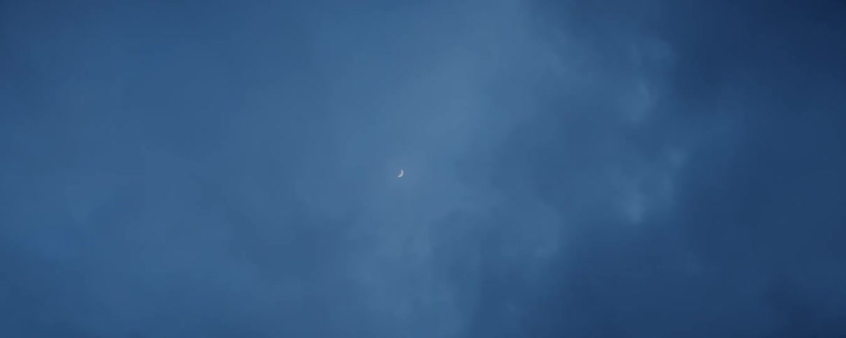 The moon glows lightly through clouds