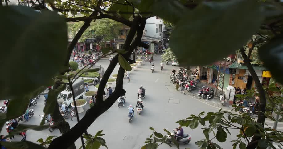 People ride on motorbikes through a crowded city