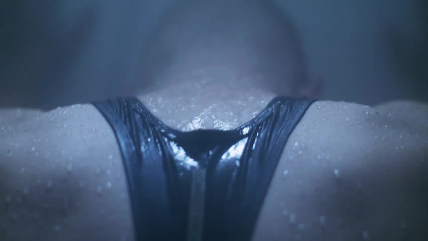 Man stands and looks down while water pours off his back