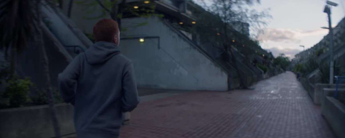 Man is jogging on path in residential area at dawn