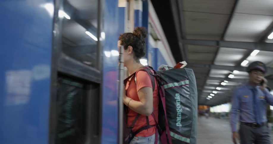 Woman smiles as she boards a train wearing her luggage