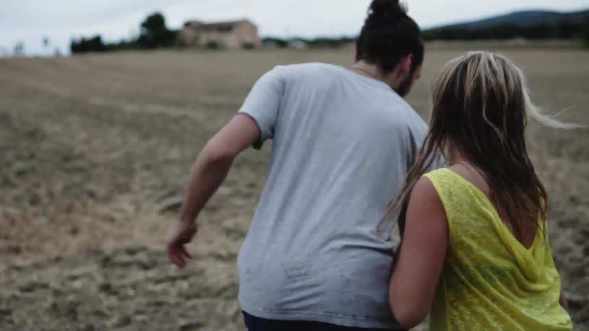 Man and woman walk and run in a field