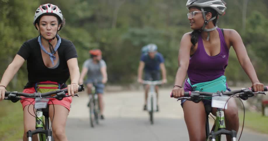 Women are talking while riding bicycles on road