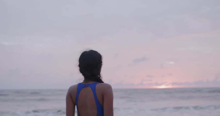 Woman walks on the beach at sunset