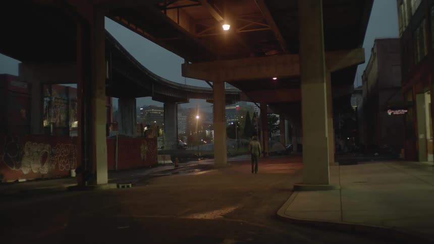 The person walks under the overpass at dawn