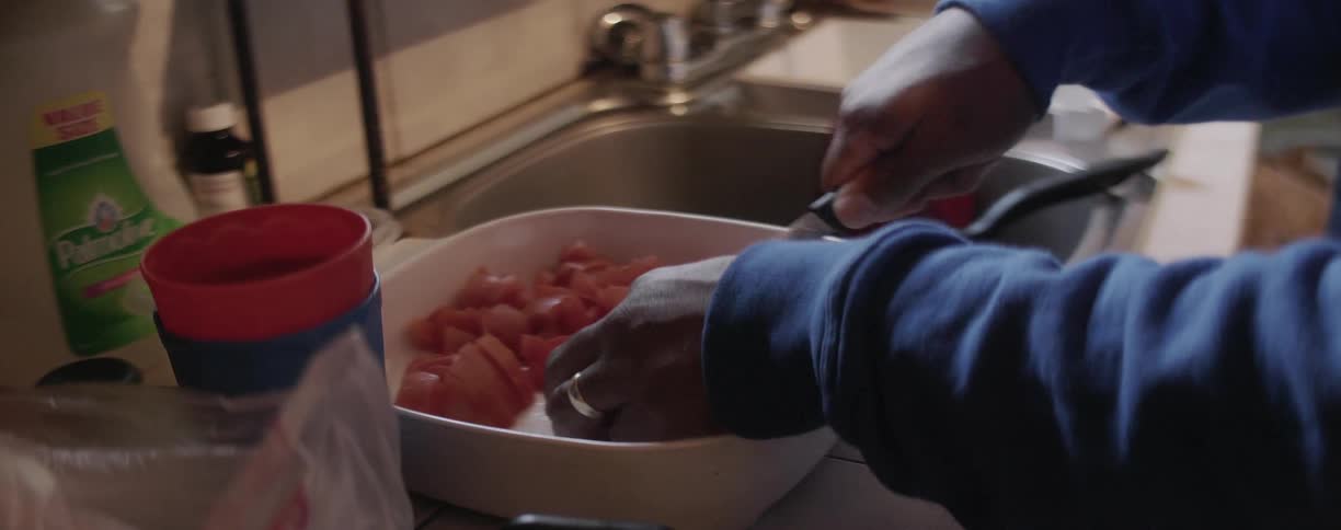 A person slices tomatoes in the kitchen