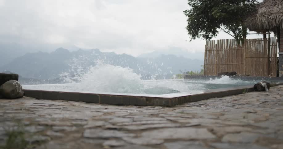 Two men run and jump into pool on cloudy day