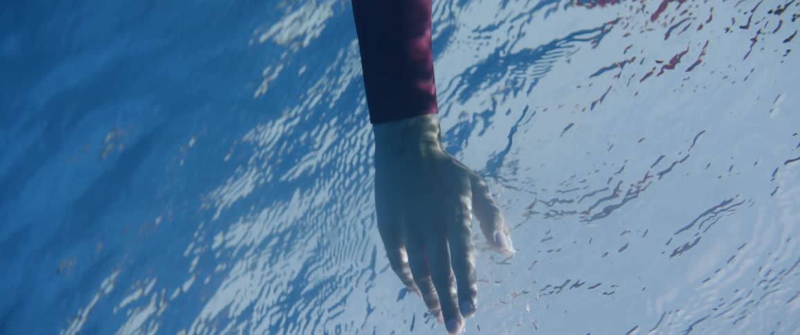 Woman runs her hand through the ripples of the water