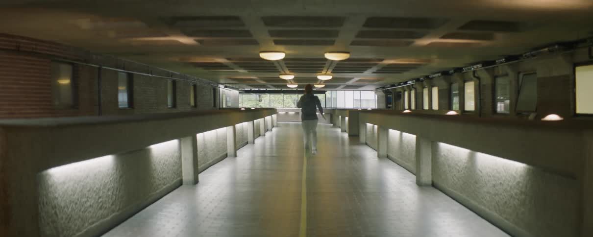 A man is sprinting through a hallway inside a building in daylight