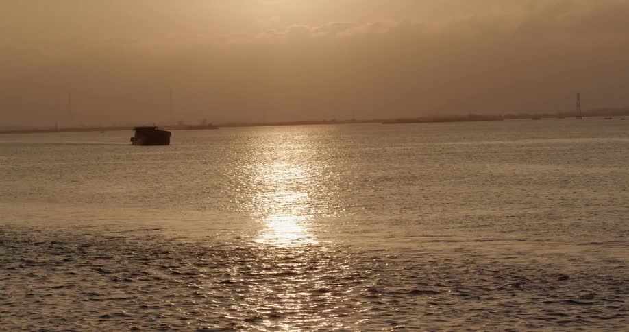 A boat is sailing on the ocean at sunset