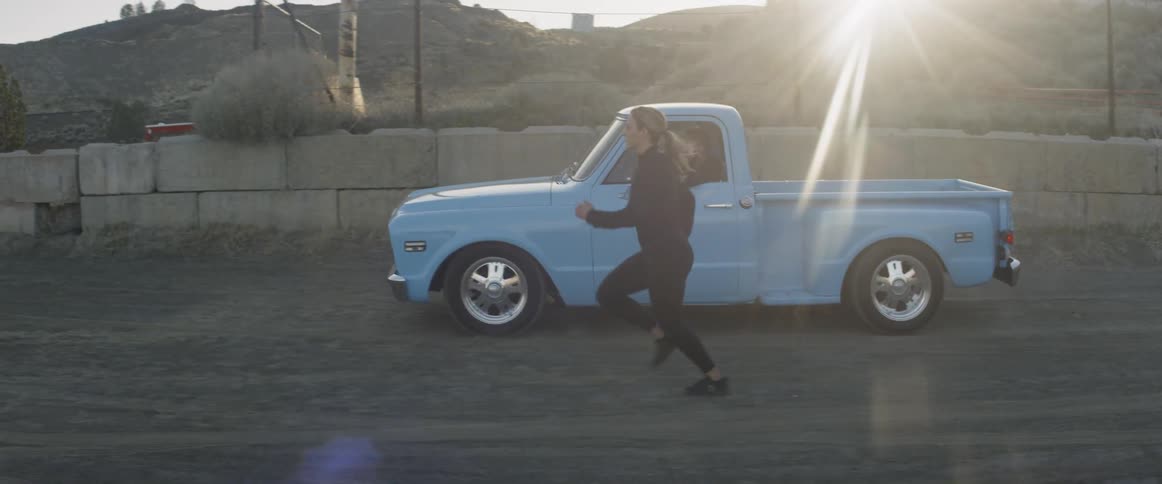 A woman runs alongside a pickup truck