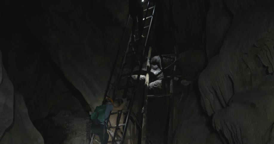 People climb down a ladder in a cave