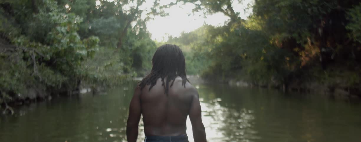 Man is wading into water hole in the forest