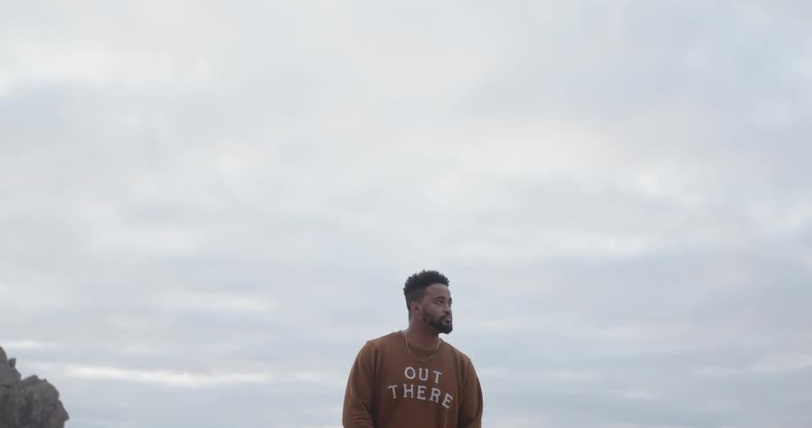 The man stands by the shore waving his arms