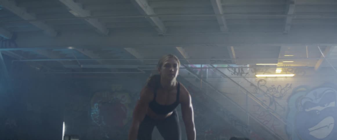 Woman lifts weights in a wet warehouse