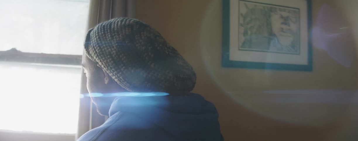Man wearing a hooded sweatshirt looks out the window