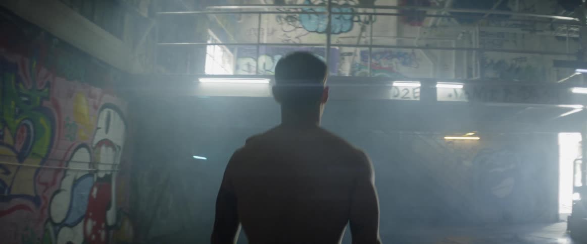 A man walks in the dark room towards the door