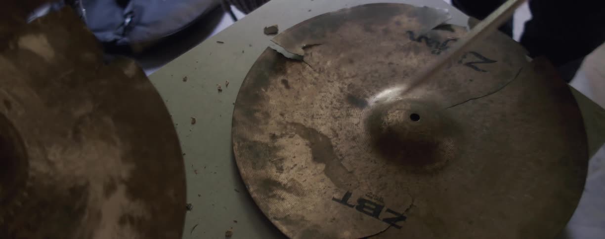 Person is hitting broken cymbal with drum sticks