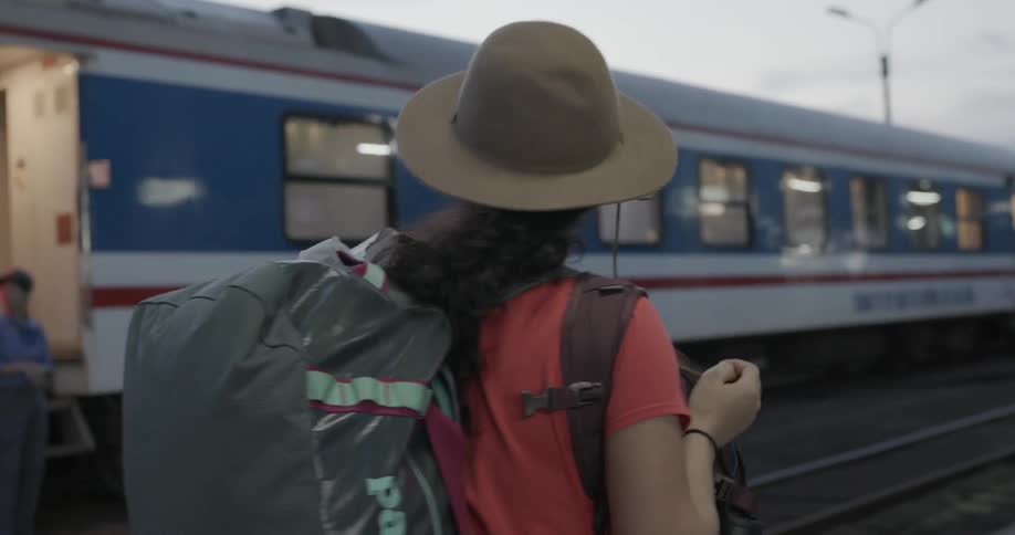 Woman walking outside a train carrying several bags