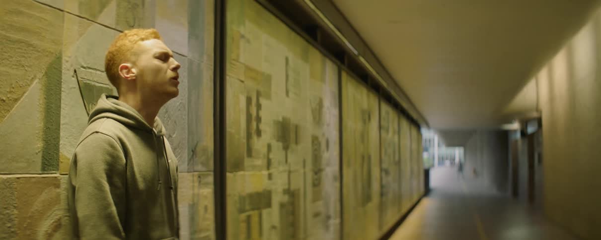 A man leans forward against the wall breathing heavy
