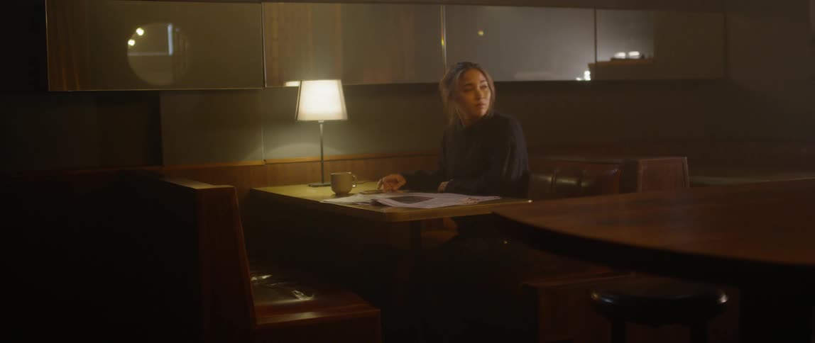 Woman reads a newspaper in a diner booth