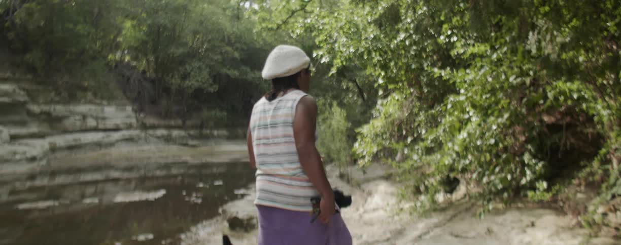 A man walks with his dog along the river bank
