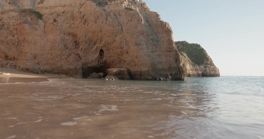 Water splashes to shore near large formations of rock