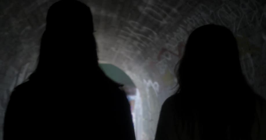 Two girls are walking through a tunnel in an urban setting in daylight