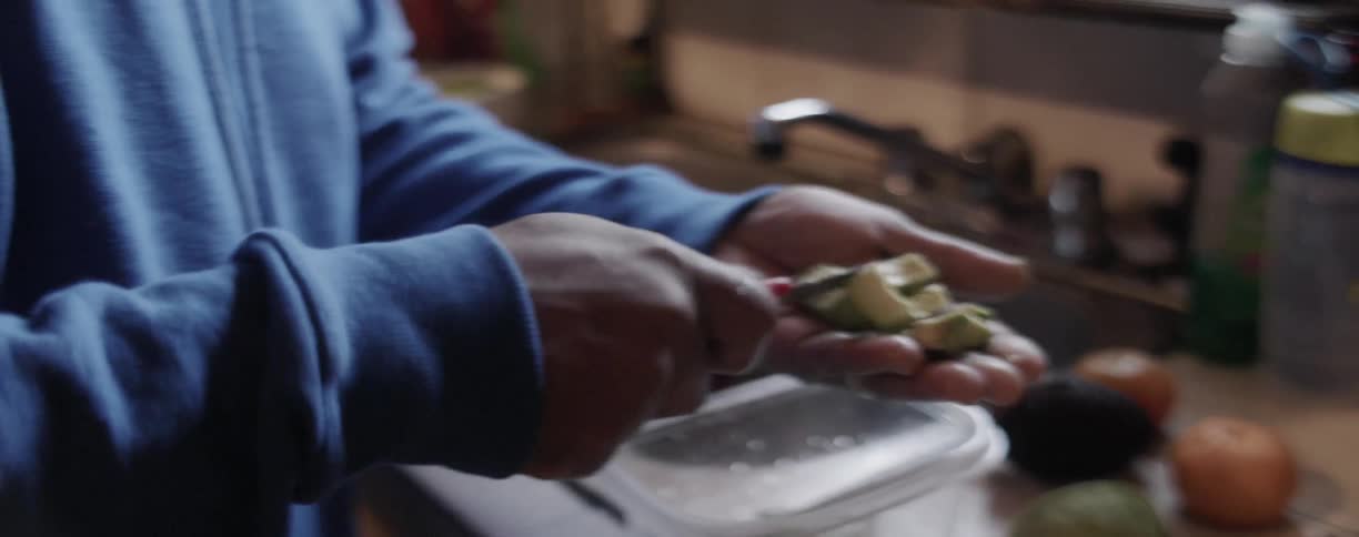 Man is chopping avocado on his hand