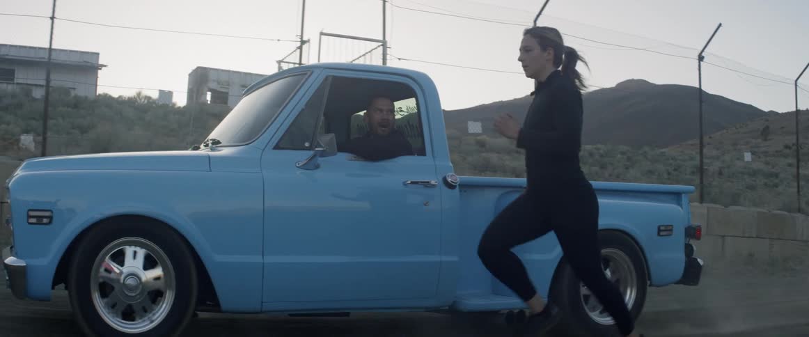 A woman runs alongside a blue pickup truck