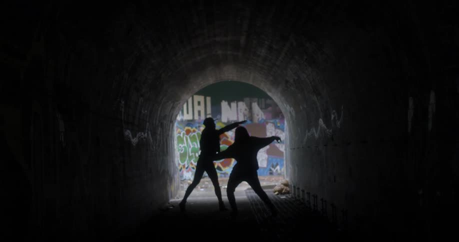 Two women dance in a tunnel