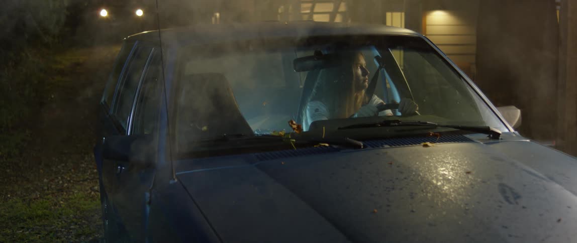 A woman sits in the driver seat of a parked car