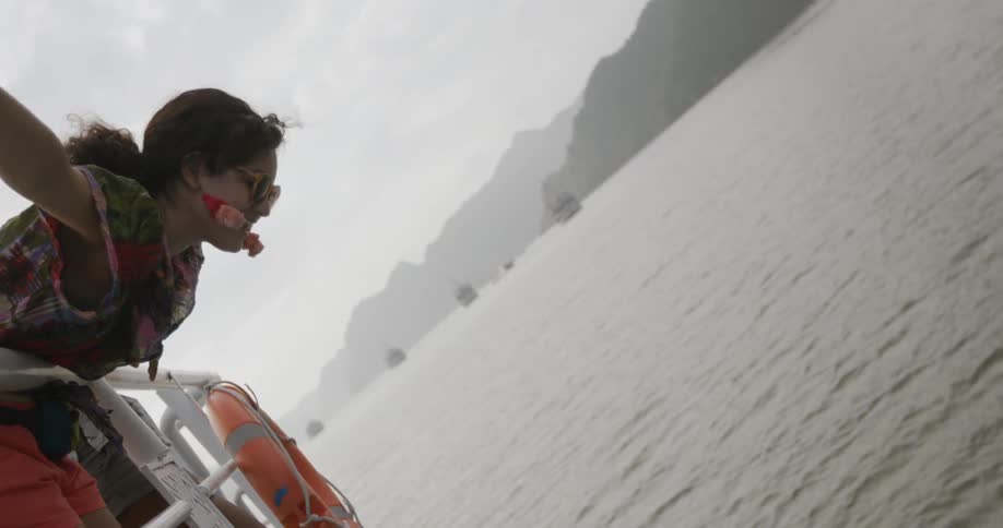 Woman leans over the edge of a boat towards water