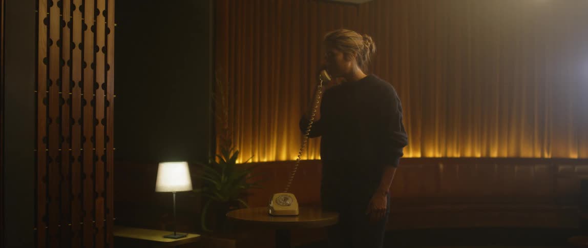 A woman walks over to a table and answers a phone then hangs up