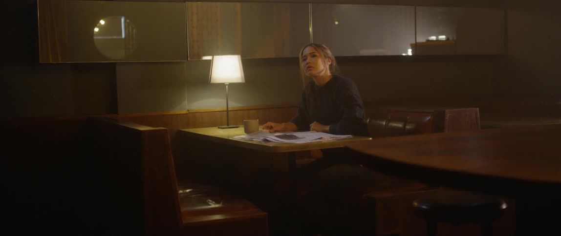 Woman reads a newspaper in a diner booth