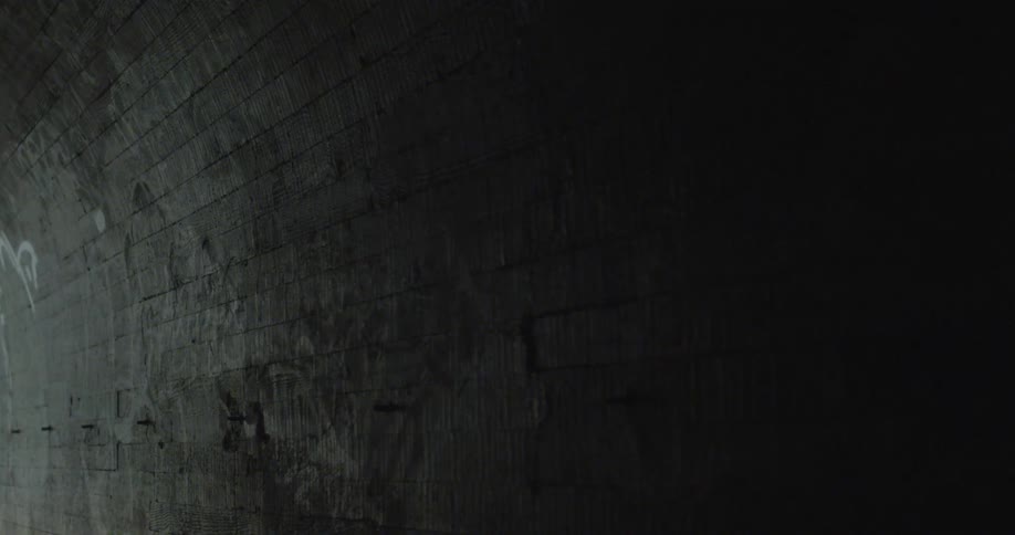 The stone wall is covered with shadows in the tunnel