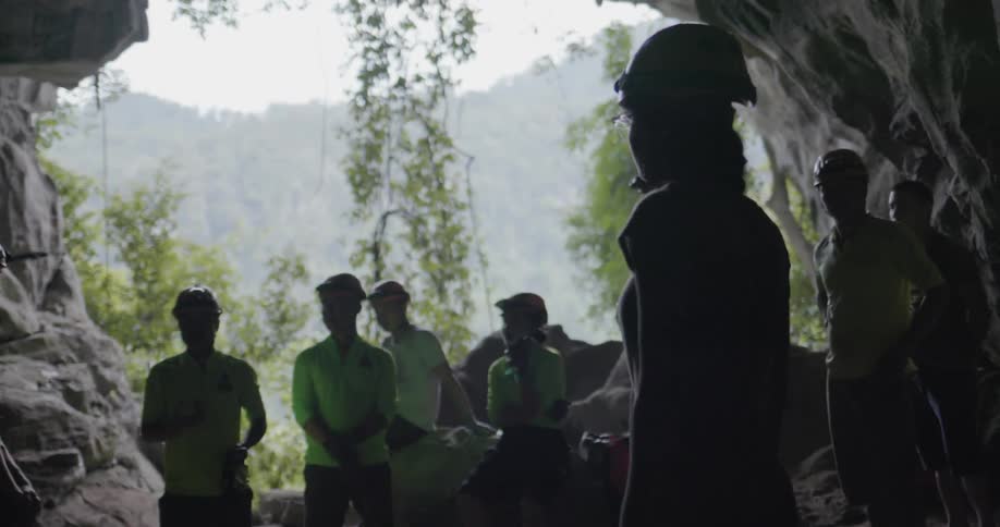 Groups of people stand at the entrance to a cave