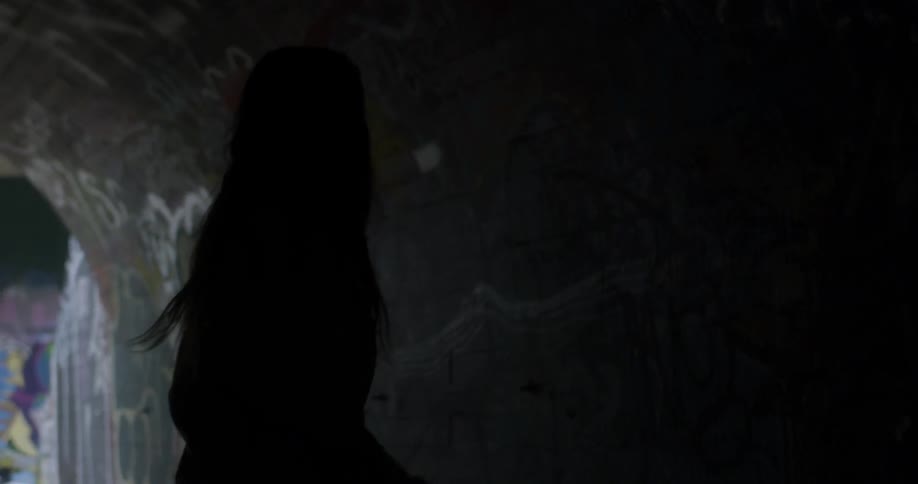 Two girls are dancing inside a tunnel in an urban setting in daylight